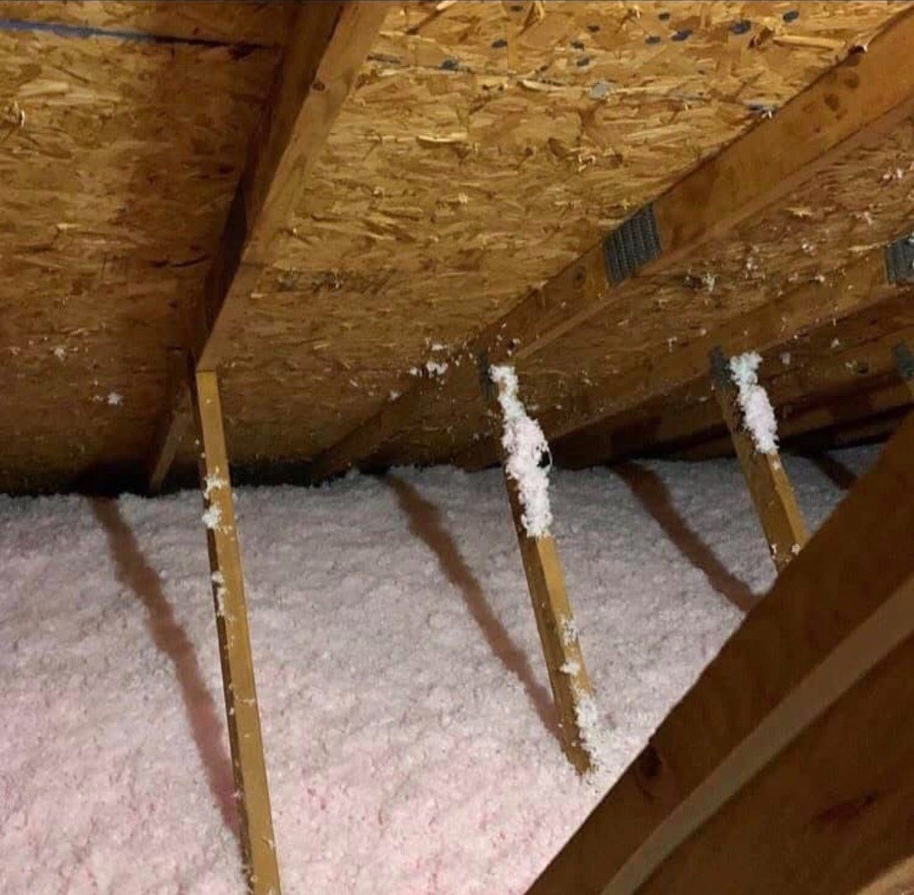 Close-up of blown-in insulation around attic framing